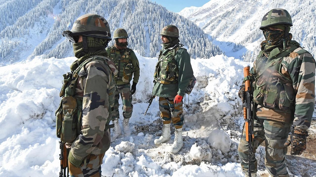 Indian army soldiers stand on a snow-covered road near Zojila mountain pass that connects Srinagar to the union territory of Ladakh, bordering China on February 28, 2021. Credit: AFP File Photo
