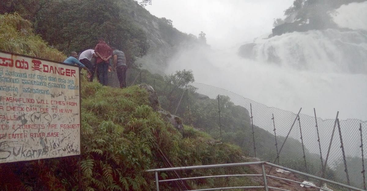 Tourists cross the fence to go near the falls, inviting danger.