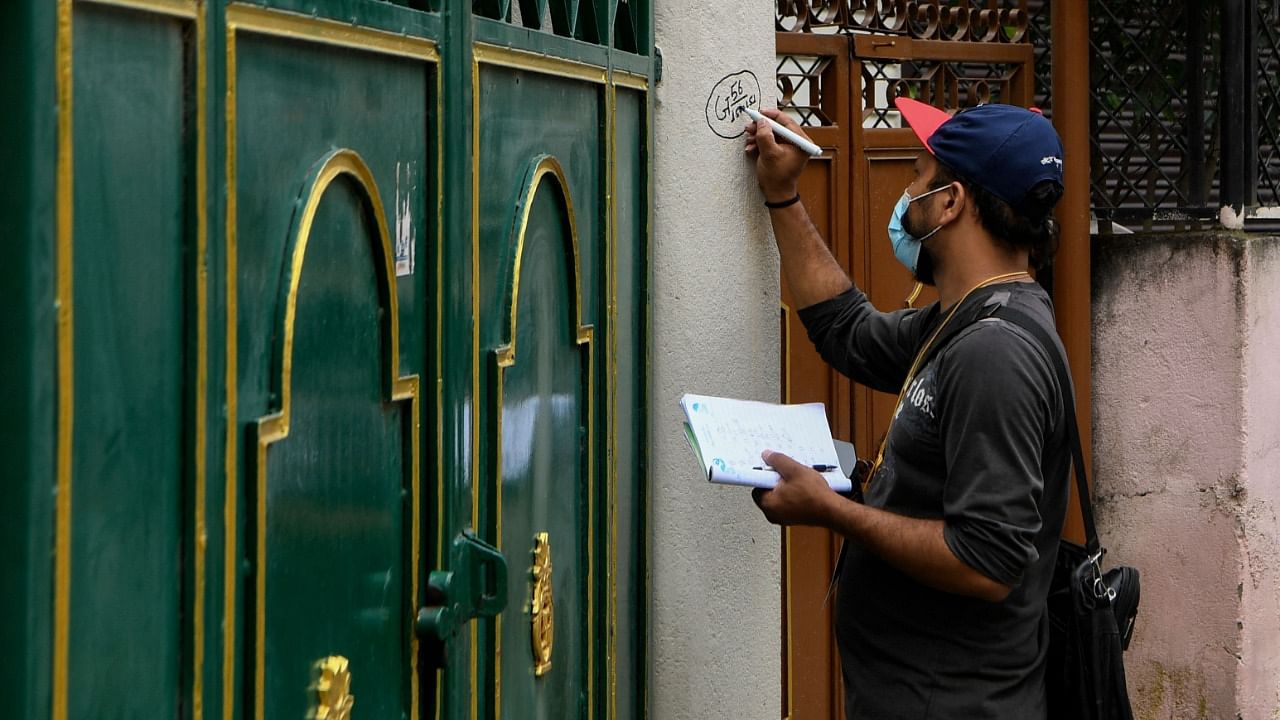 An enumerator marks the entrance of a house during house and household data collection for the 2021 population census conducted by the Central Bureau of Statistics, in Kathmandu on September 29, 2021. Credit: AFP Photo