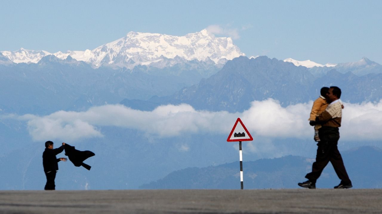 A man with a child walks in front of the Gankar Punsun glacier at Dochula in Bhutan. Credit: Reuters Photo