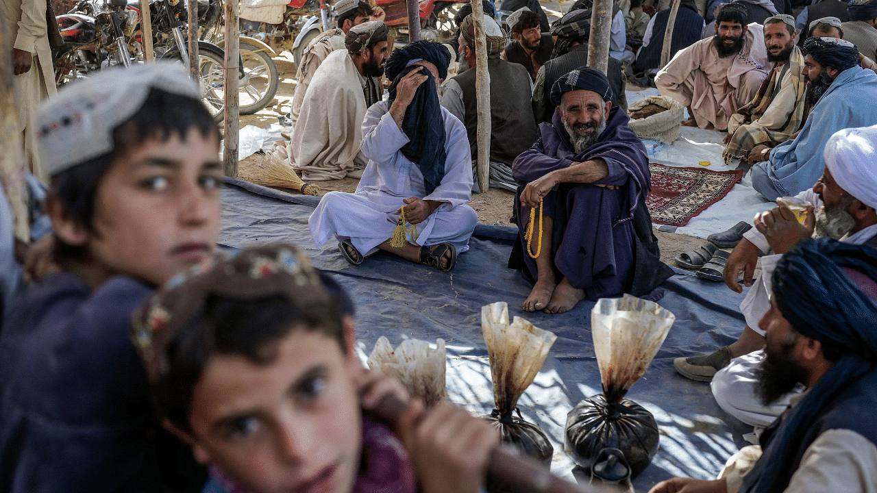 Men gather around bags containing heroin and hashish in Afghanistan. Credit: AFP Photo