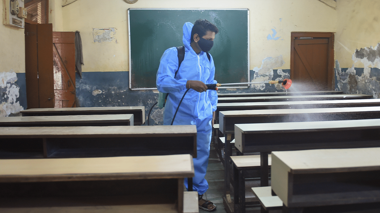  A worker sanitises a classroom of the Gandhi Memorial English High School after Maharashtra government allowed schools to reopen for VIIIth to XIIth classes. Credit: PTI Photo