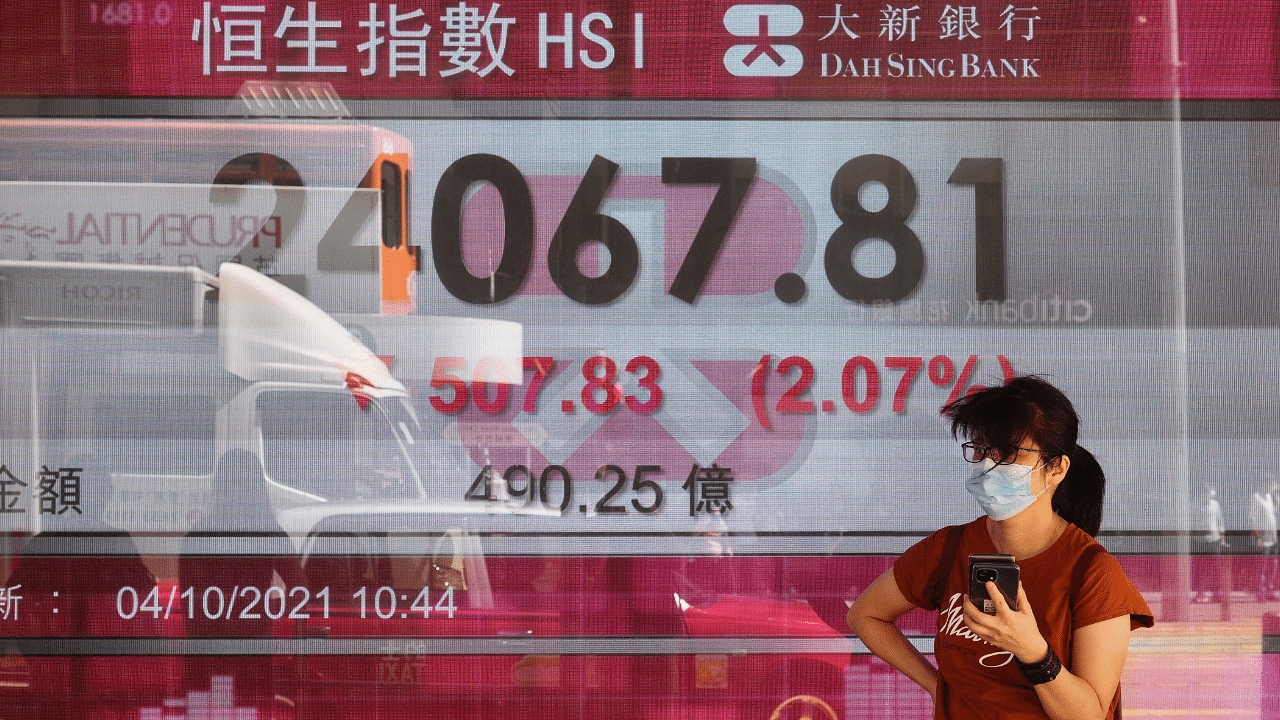 A woman walks past a bank's electronic board showing the Hong Kong share index at Hong Kong Stock Exchange in Hong Kong. Credit: AP Photo