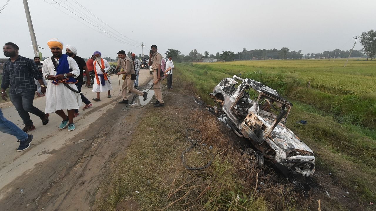People take a look at the overturned SUV which destroyed in Sunday's violence during farmers' protest, at Tikonia area of Lakhimpur Kheri district. Credit: PTI Photo
