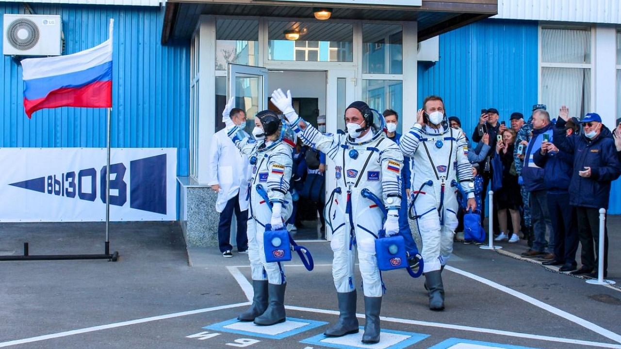 This handout photo taken and released on October 5, 2021 by Russian Space Agency Roscosmos shows crew members, cosmonaut Anton Shkaplerov (C), actress Yulia Peresild (L) and film director Klim Shipenko waving prior to board the Soyuz MS-19 spacecraft ahead of its launch at the Russian-leased Baikonur cosmodrome. Credit: AFP Photo/Roscosmos