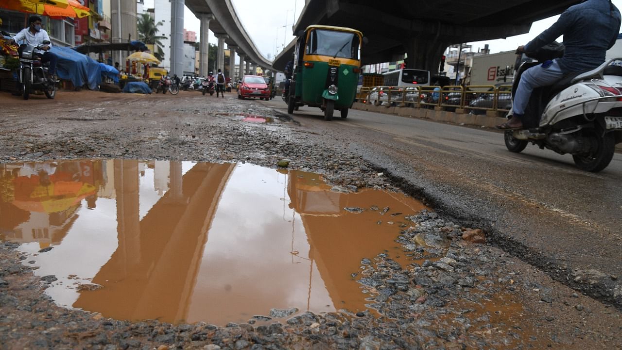 Motorists struggle to navigate on a stretch of bad road ridden with potholes. Credit: DH File Photo/B H Shivakumar