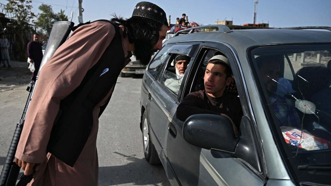 A Taliban fighter working as part of a police force checks commuters at a road checkpoint in Kabul. Credit: AFP Photo