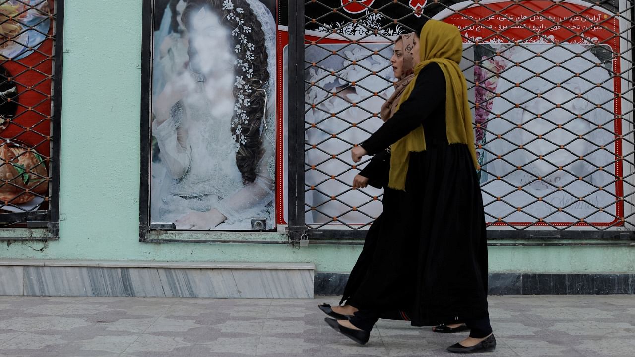 Women walk past a shop with defaced pictures of women in Kabul. Credit: Reuters Photo