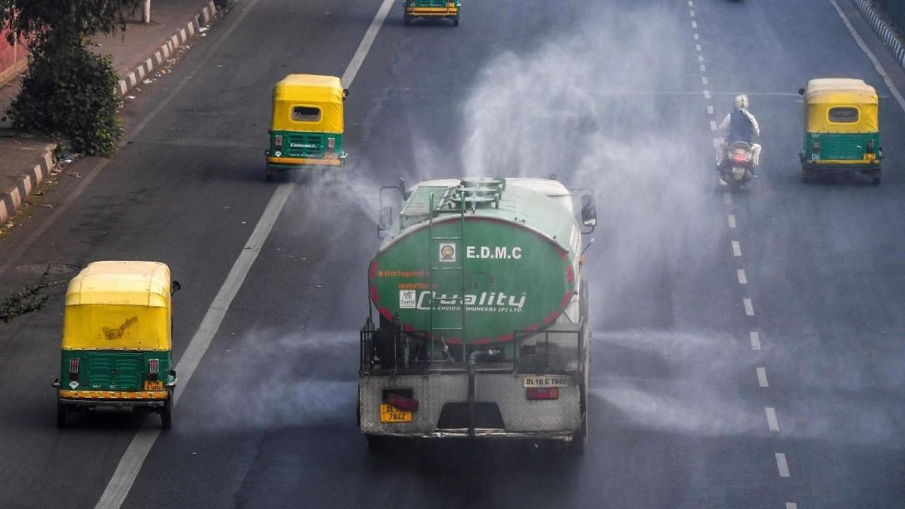 EDMC vehicle sprinkles water to control dust as commuters drive along a road amid smoggy conditions in New Delhi. Credit: AFP File Photo