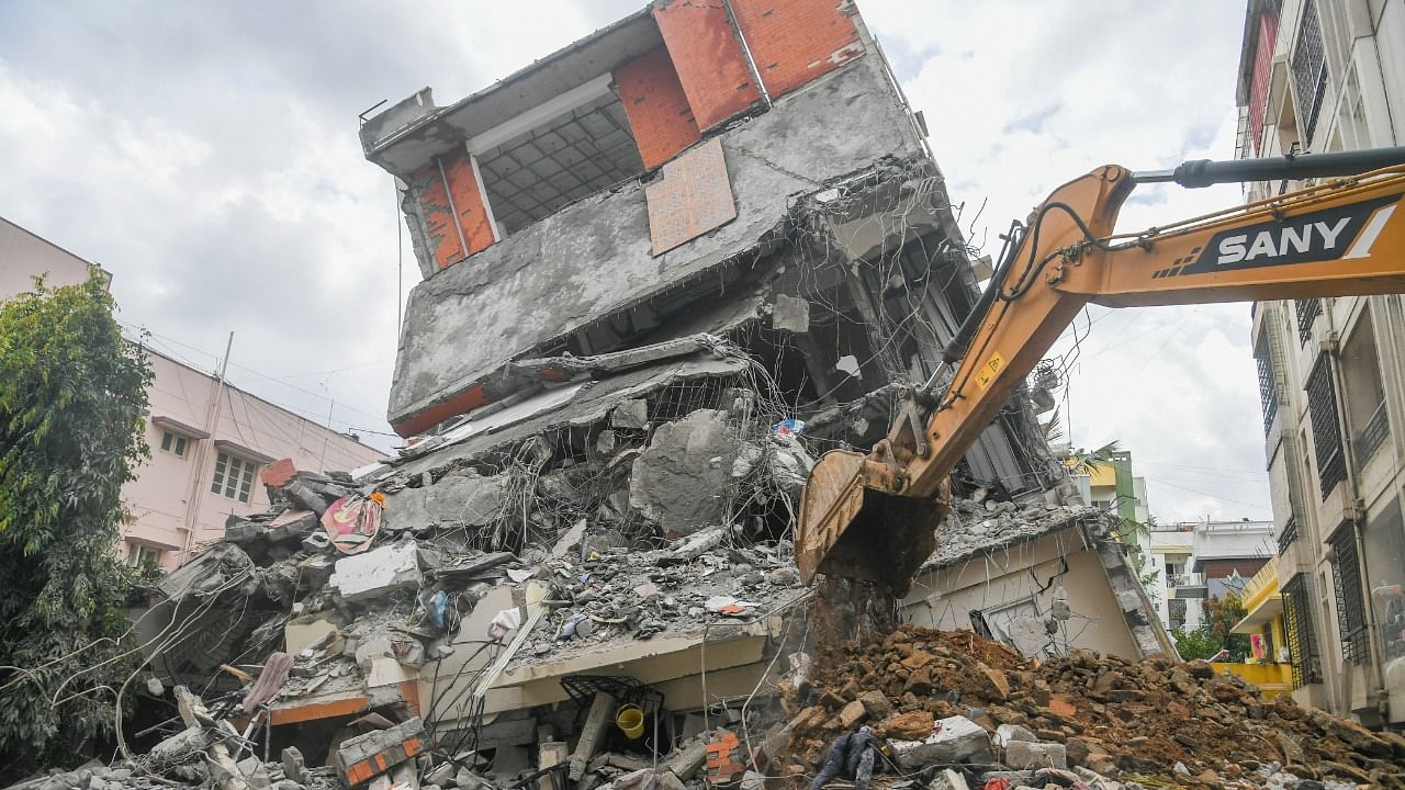 After the building tilted dangerously and its ground floor gave way on Thursday, municipal authorities started pulling it down. Credit: DH Photo/S K Dinesh