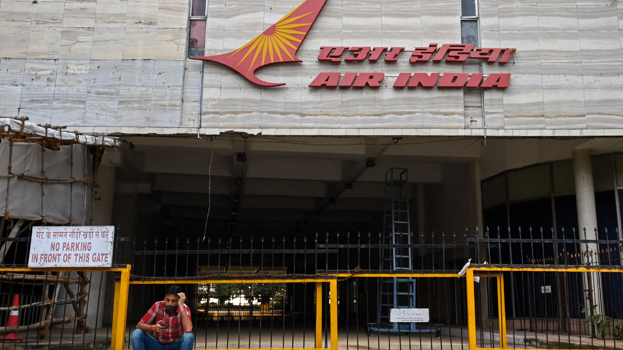 A man checks his mobile phone as he sits outside the Air India building in Mumbai. Credit: AFP Photo
