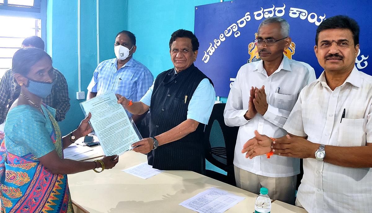 MLA K G Bopaiah distributes a cultivation chit to a beneficiary coming under the Virajpet Assembly constituency in Madikeri taluk.