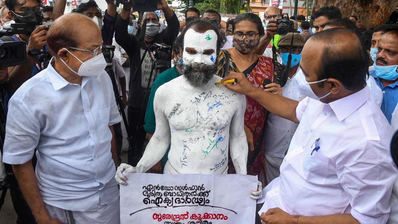 Leader of Opposition in Kerala Assembly VD Satheesan and Dy leader P K Kunhalikutty put their signatures on the painted bare body of a protester seeking justice for endosulfan victims, in Thiruvananthapuram. Credit: PTI Photo