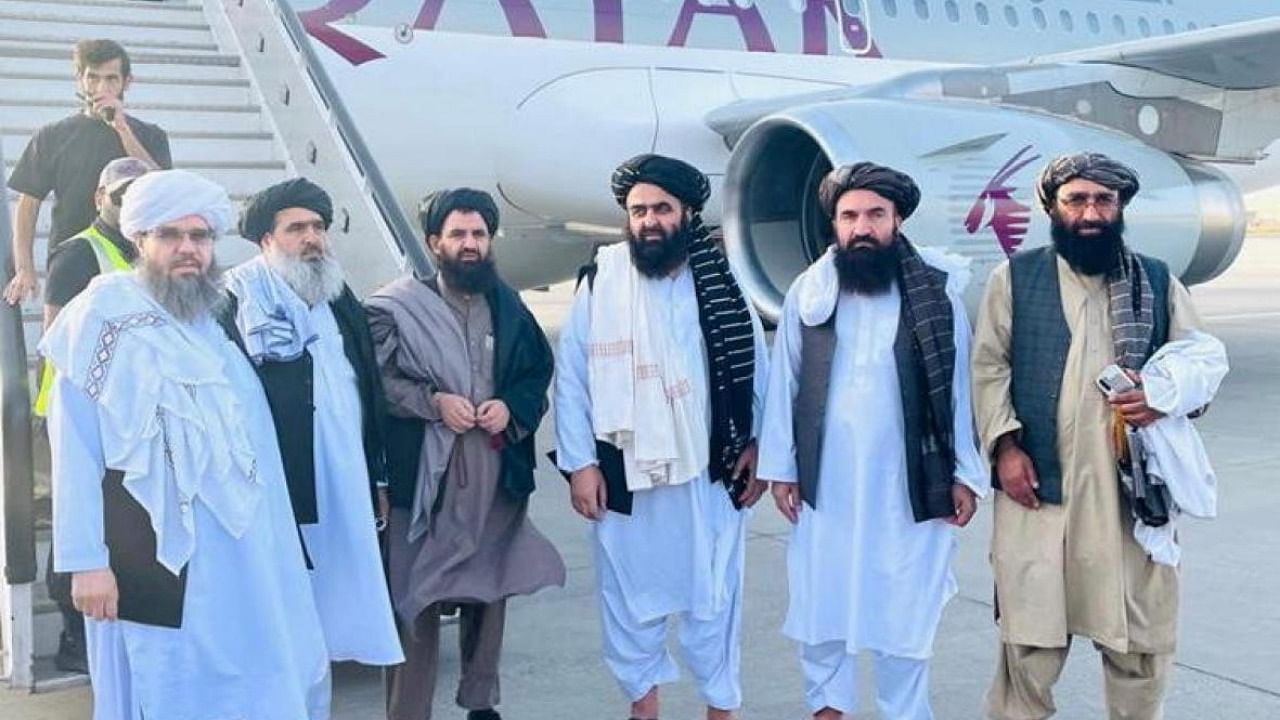 Taliban delegates stand in front of a Qatar Airways plane in an unidentified location in Afghanistan, in this handout photo uploaded to social media. Credit: Reuters photo