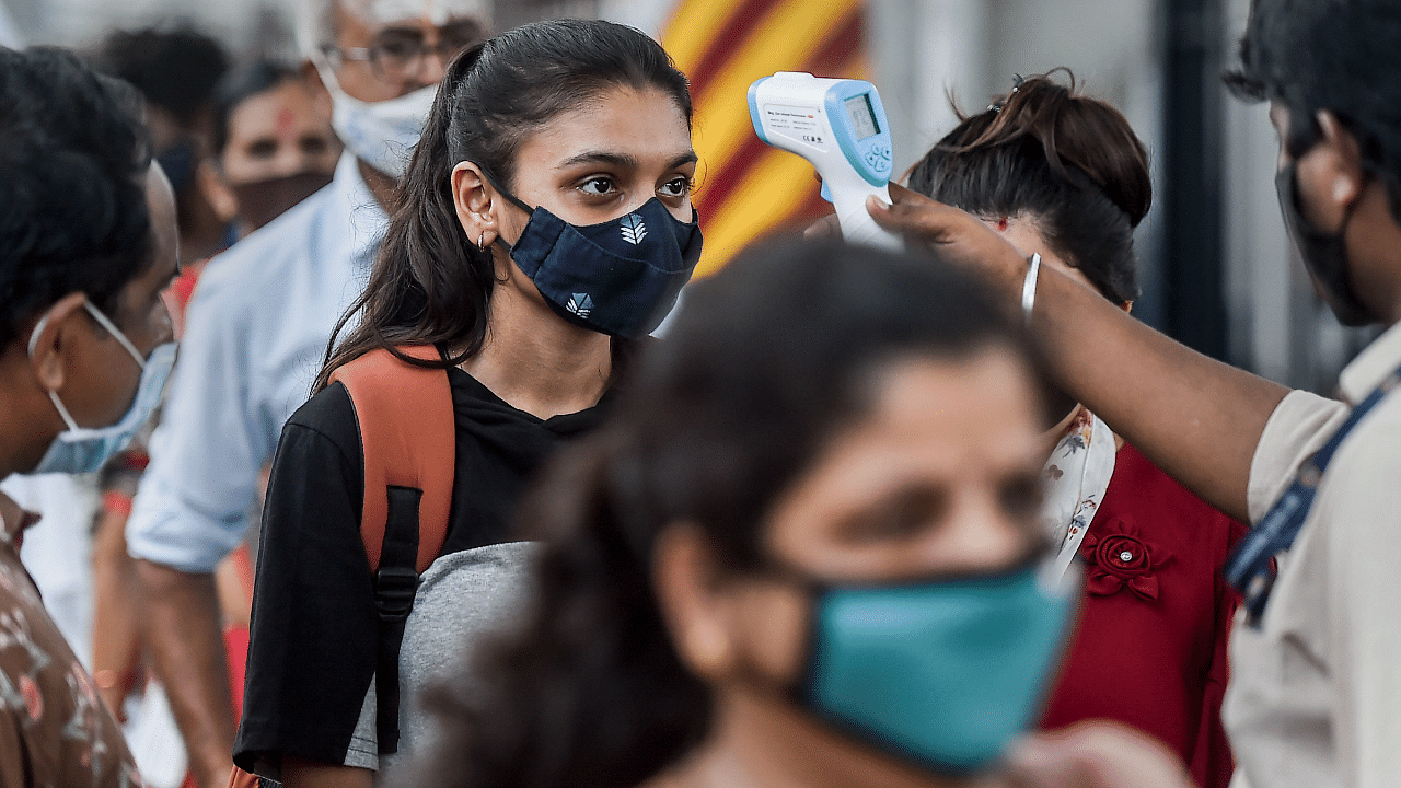 A health worker checks body temperature of a traveler as a precaution against the coronavirus before allowing her to proceed at a railway station in Mumbai. Credit: PTI Photo