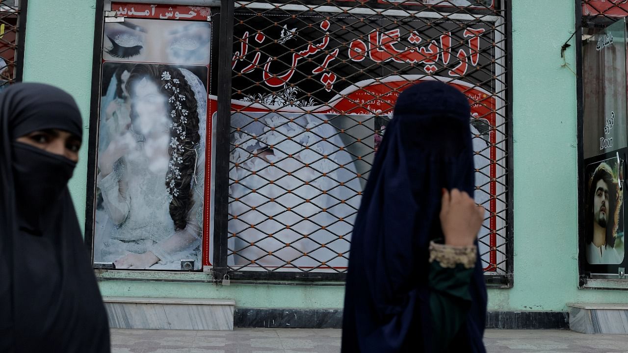 Women walk past a shop with defaced pictures of women in Kabul, Afghanistan October 6, 2021. Credit: Reuters Photo