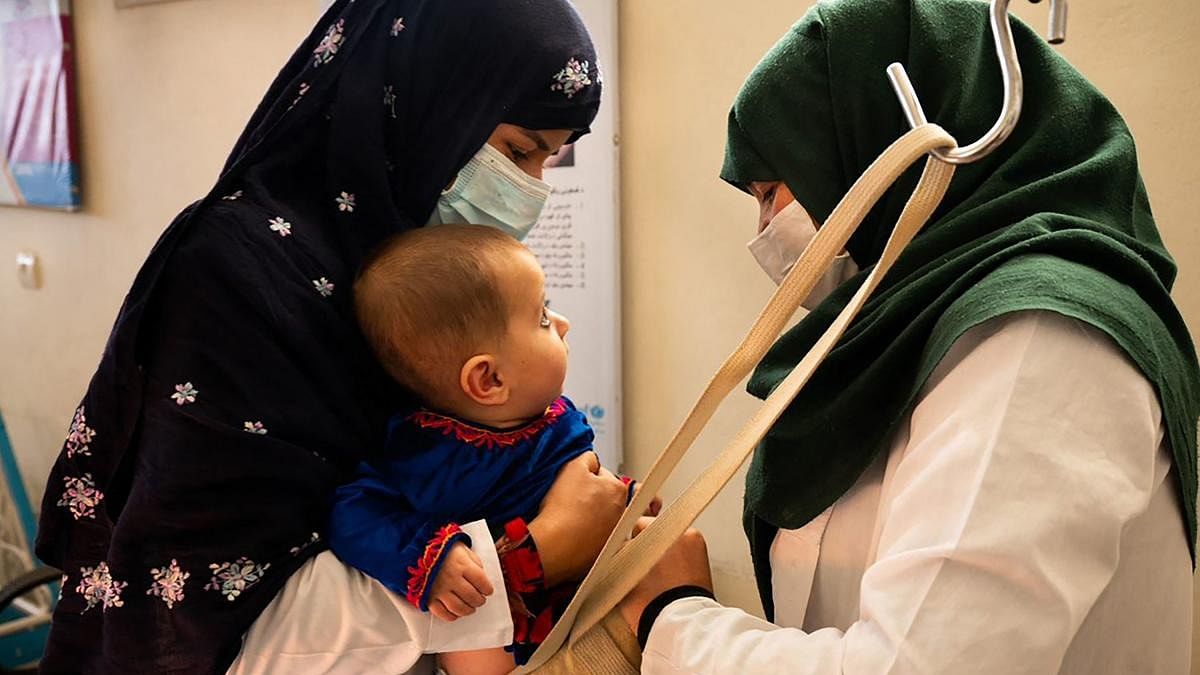A midwife (L) and a nutrition counsellor weighing a baby at the Tangi Saidan clinic run by the Swedish Committee for Afghanistan, in Daymirdad district of Wardak province. Credit: AFP Photo