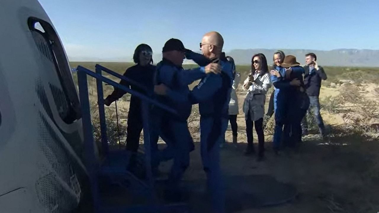 New Shepard NS-18 mission crew member "Star Trek" actor, William Shatner (CL) gets a hug from Blue Origin founder Jeff Bezos on October 13, 2021, after landing in the West Texas region. Credit: AFP Photo