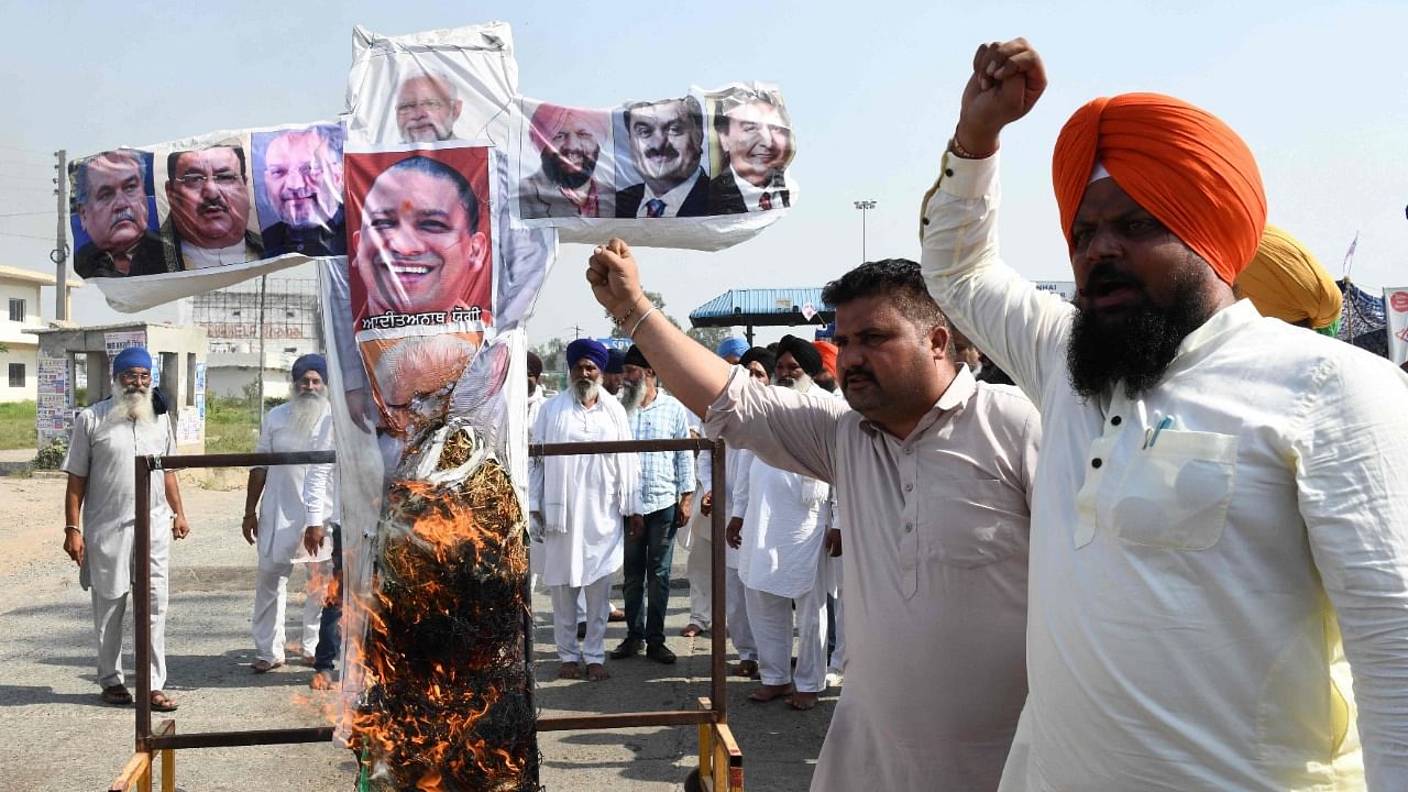 Farmers shout slogans as they burn an effigy with the pictures of PM Modi and Amit Shah. Credit: AFP File Photo