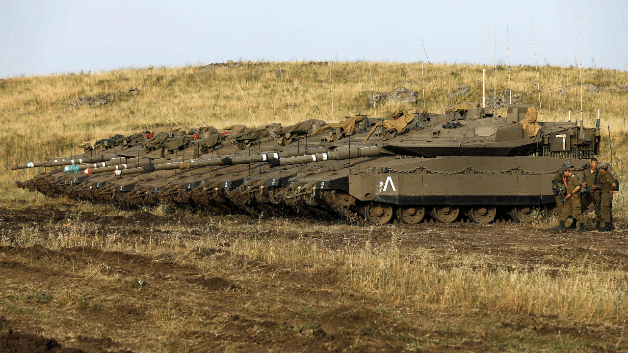 Israeli soldiers stand next to Merkava Mark IV tanks in a deployment area. Credit: AFP Photo