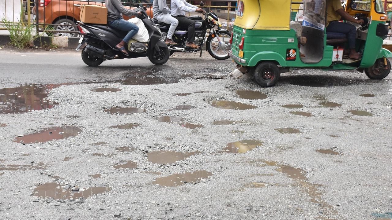 Vehicles navigate on potholes on KG road in Bengaluru on Saturday. Credit: DH File Photo