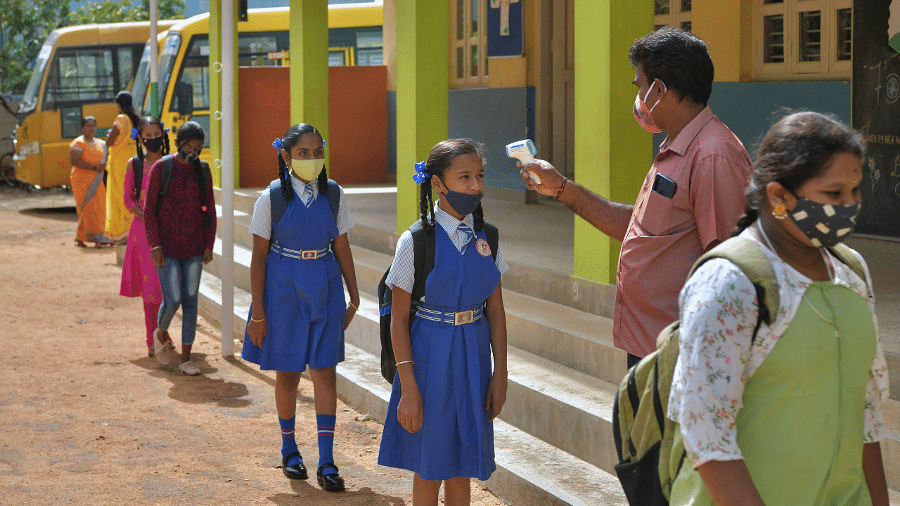 A teacher checks the body temperature of students upon their arrival at a school in Bangalore. Credit: AFP Photo