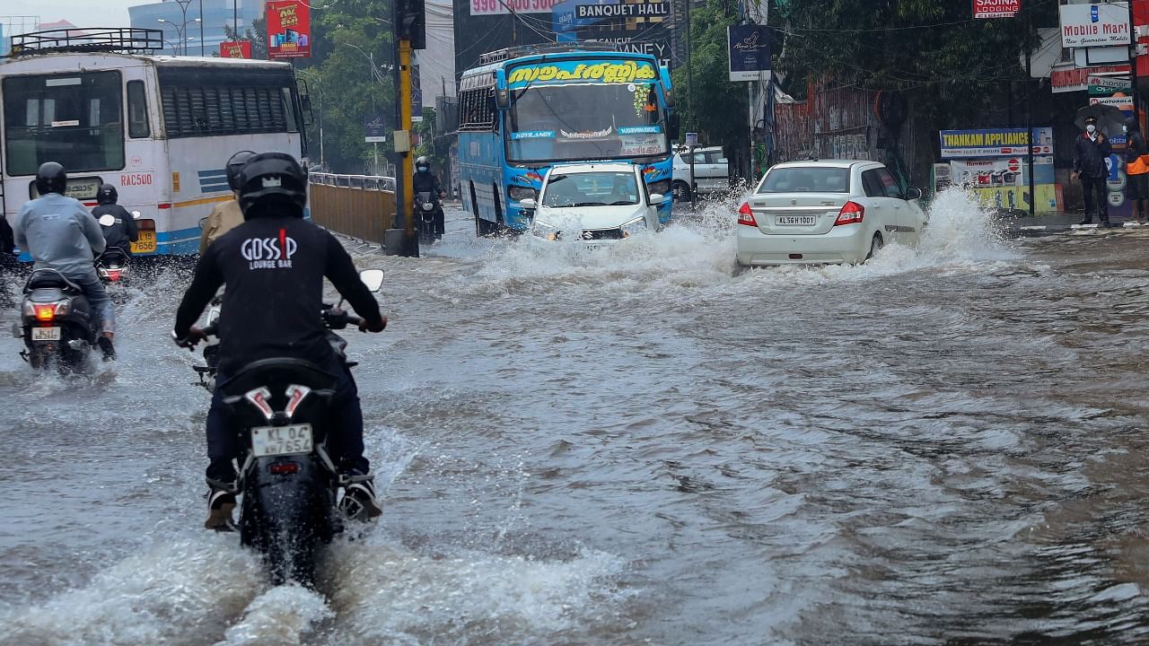 Commuters wade through a waterlogged road during heavy rain in Kozhikode. Credit: PTI Photo