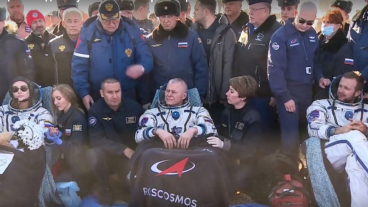 Roscosmos cosmonaut Oleg Novitskiy (C), Russian actress Yulia Peresild (L) and film director Klim Shipenko rest on chairs after landing. Credit: AFP Photo