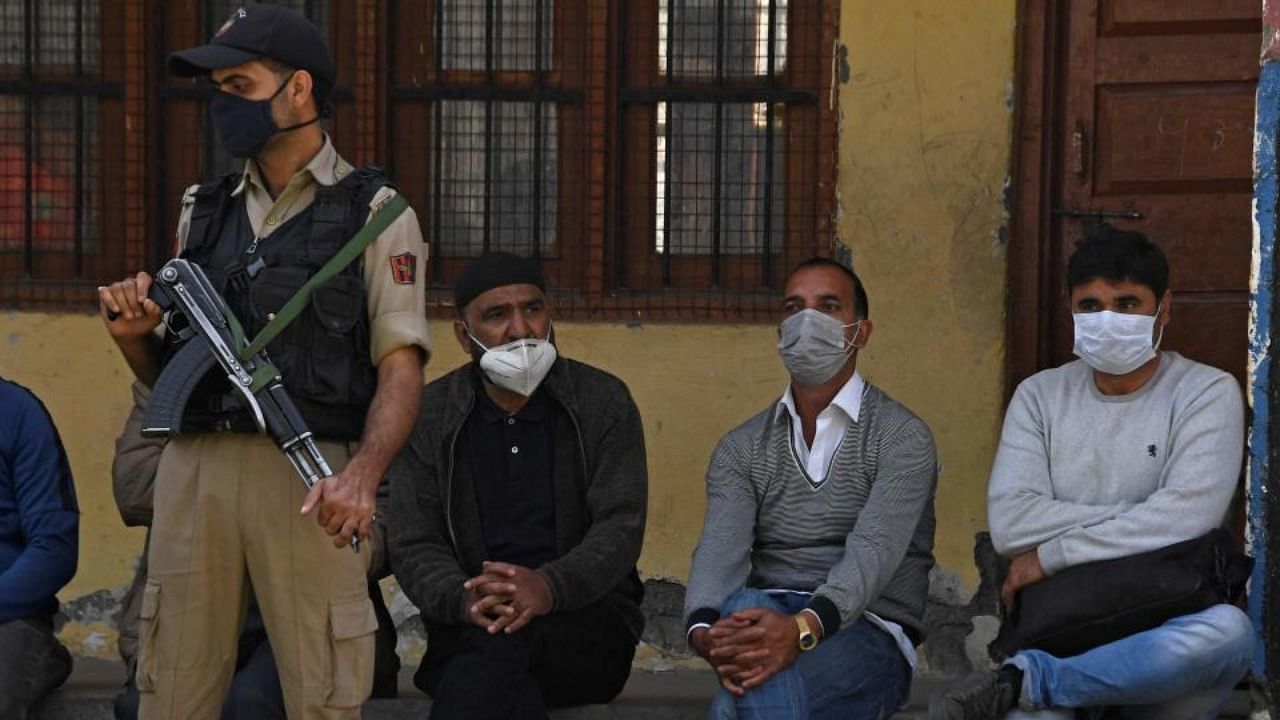 In this file photo taken on October 7, 2021, a policeman stands guard next to teachers inside a government-run school on the outskirts of Srinagar after suspected anti-India militants shot dead two schoolteachers in Kashmir. Credit: AFP Photo