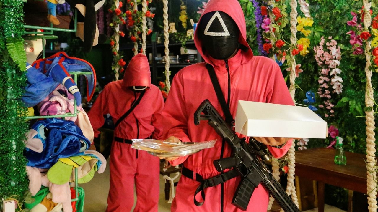 Waiters wearing "Squid Game" costumes carry trays with dalgona honeycomb toffee at Strawberry Cafe in Jakarta, Indonesia. Credit: Reuters File Photo