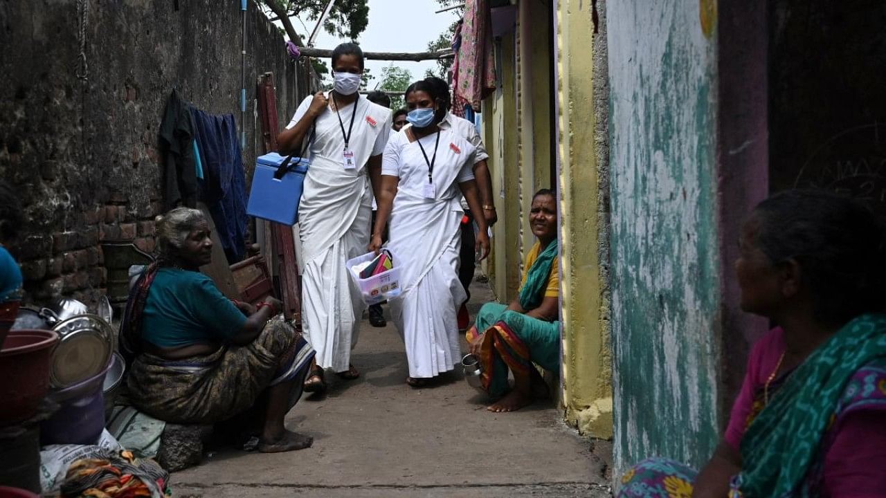 Health workers walk along an alley during a door-to-door vaccination drive against the Covid-19 coronavirus at a slum in Chennai. Credit: AFP File Photo