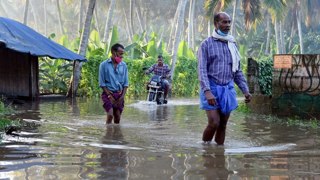 Commuters wade through a waterlogged street after heavy rain in Thiruvananthapuram. Credit: PTI Photo