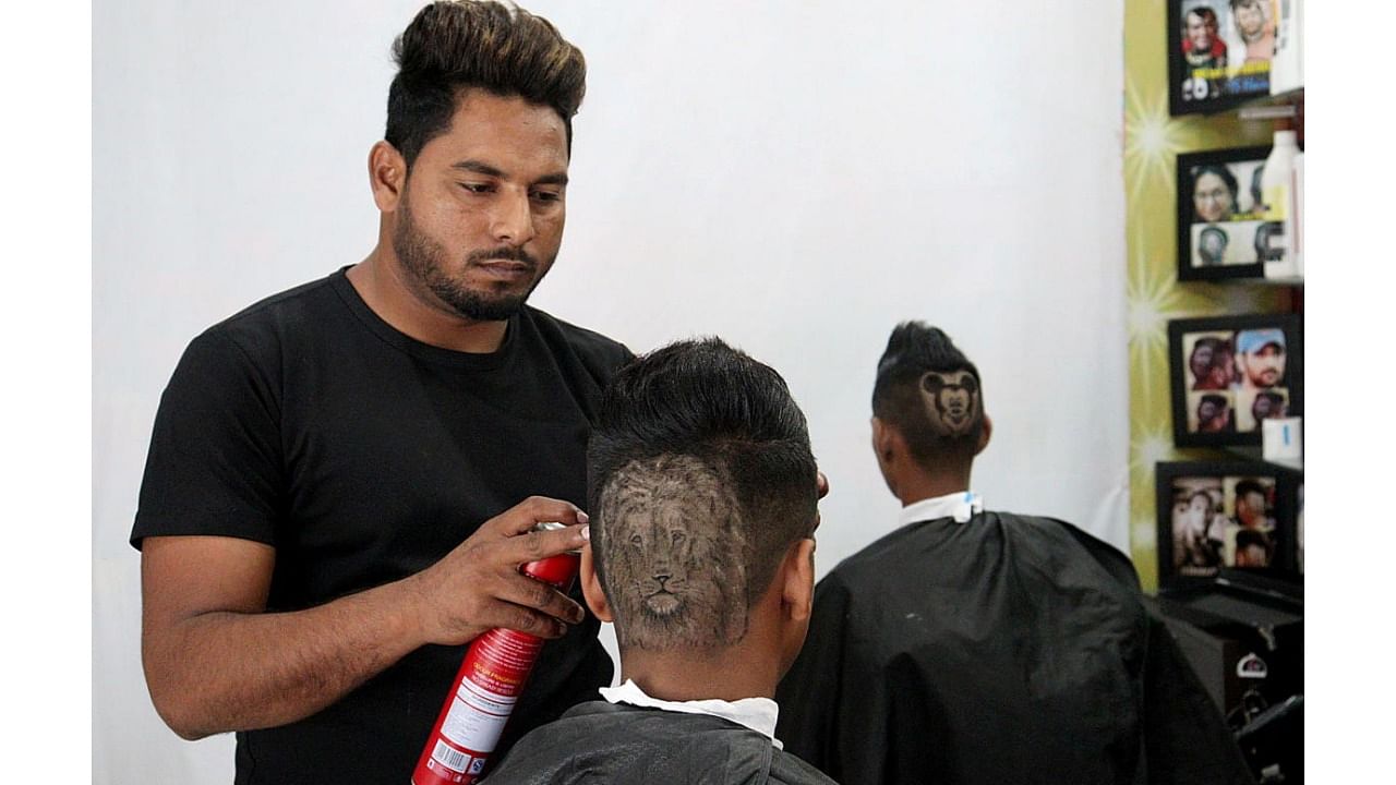 Gurwinder Singh Sidhu gives finishing touches to the hair of a customer after making a hair tattoo in the shape of a lion on his head, in Dabwali. Credit: Reuters Photo