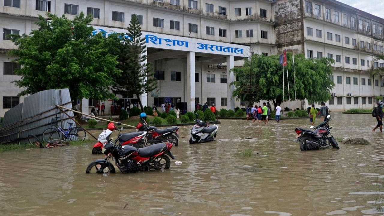 People wade through a flooded road in front of a teaching hospital after heavy rains in Biratnagar on October 20, 2021. Credit: AFP Photo