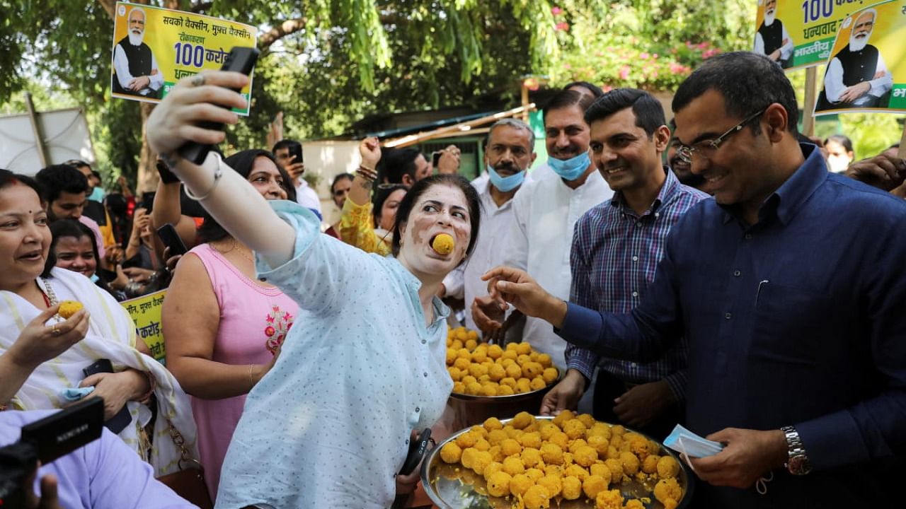 A woman takes a selfie while being fed with sweets as India celebrates the milestone of administering one billion Covid-19 vaccine doses. Credit: Reuters Photo