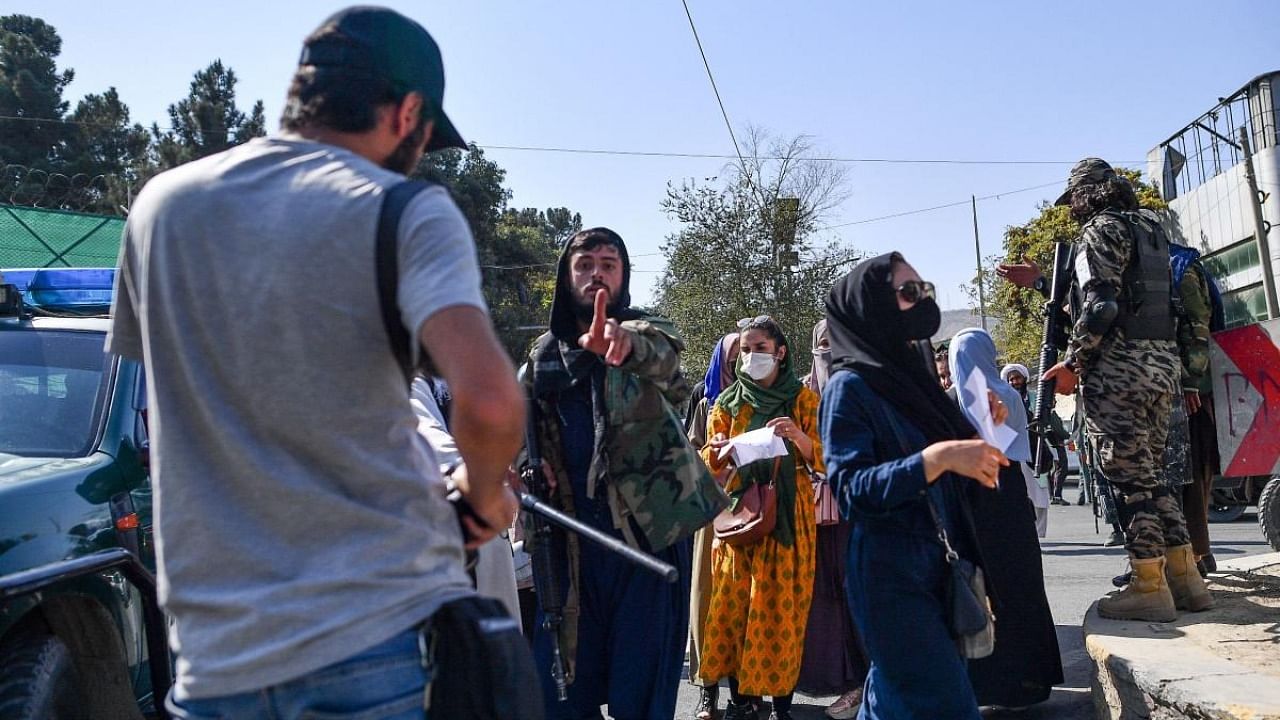 A Taliban members (C) gestures towards journalists covering a women's rights protest in Kabul. Credit: AFP Photo