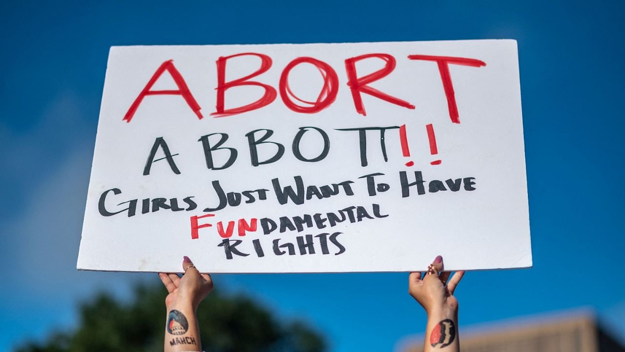 A woman holds a sign in reference to Texas Governor Greg Abbott. Credit: AFP Photo