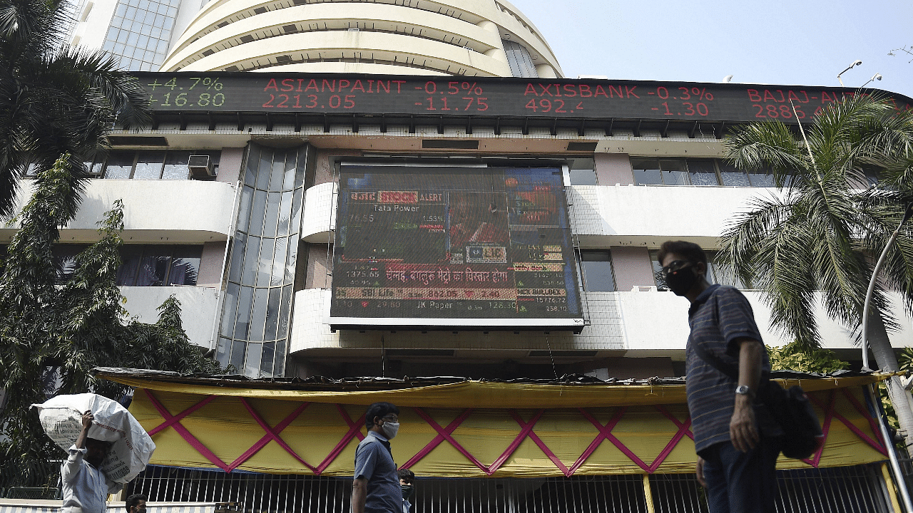 People walk past a digital screen, displaying stock prices, on the facade of Bombay Stock Exchange (BSE), in Mumbai. Credit: PTI Photo