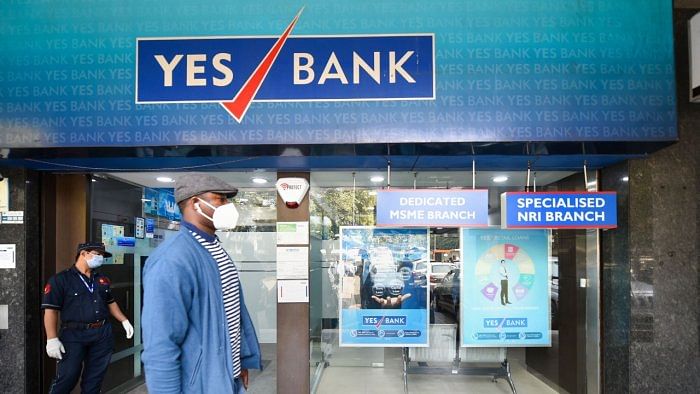 A pedestrian wears a mask to mitigate the coronavirus pandemic as he walks past a branch of Yes Bank, in New Delhi, Thursday, March 19, 2020. Credit: PTI File Photo