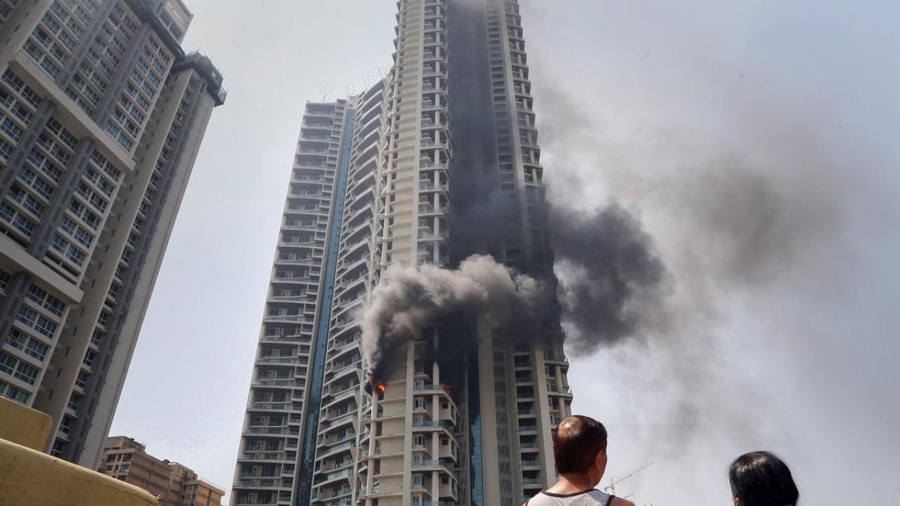 Locals look on as smoke billows from a fire at a multi-story residential building near the Lalbaug area in Parel, Mumbai. Credit: PTI Photo