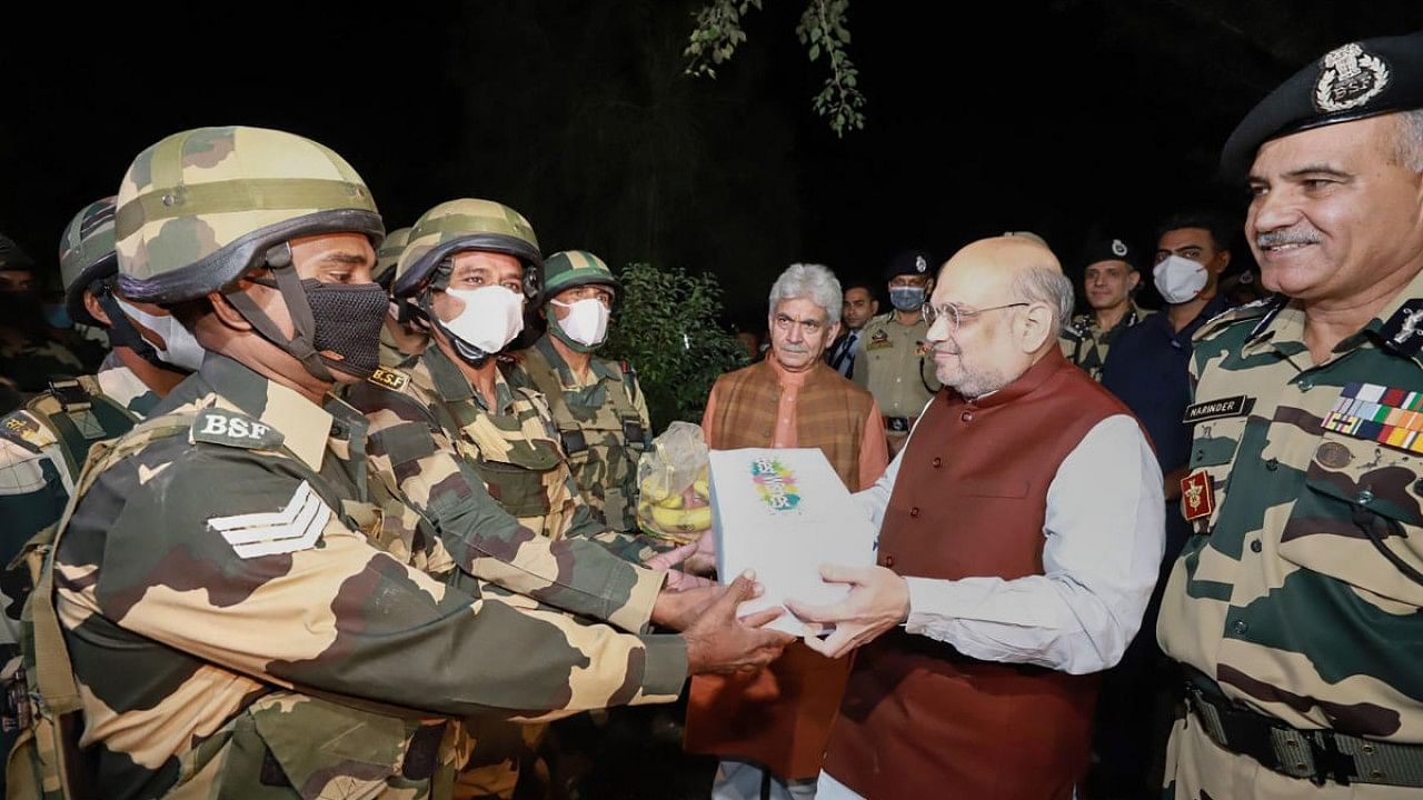Union Home Minister Amit Shah distributes sweets among BSF personnel during a visit to Maqwal. Credit: PTI Photo
