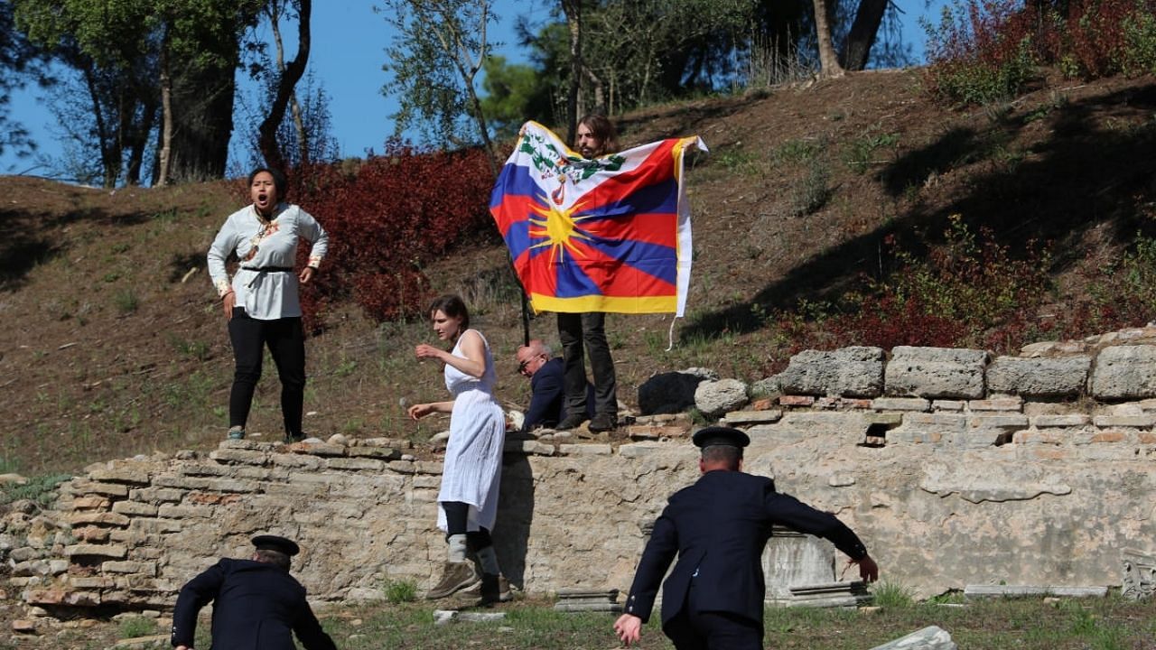 A protester holds a Tibetan flag during the Olympic flame lighting ceremony for the Beijing 2022 Winter Olympics. Credit: Reuters Photo