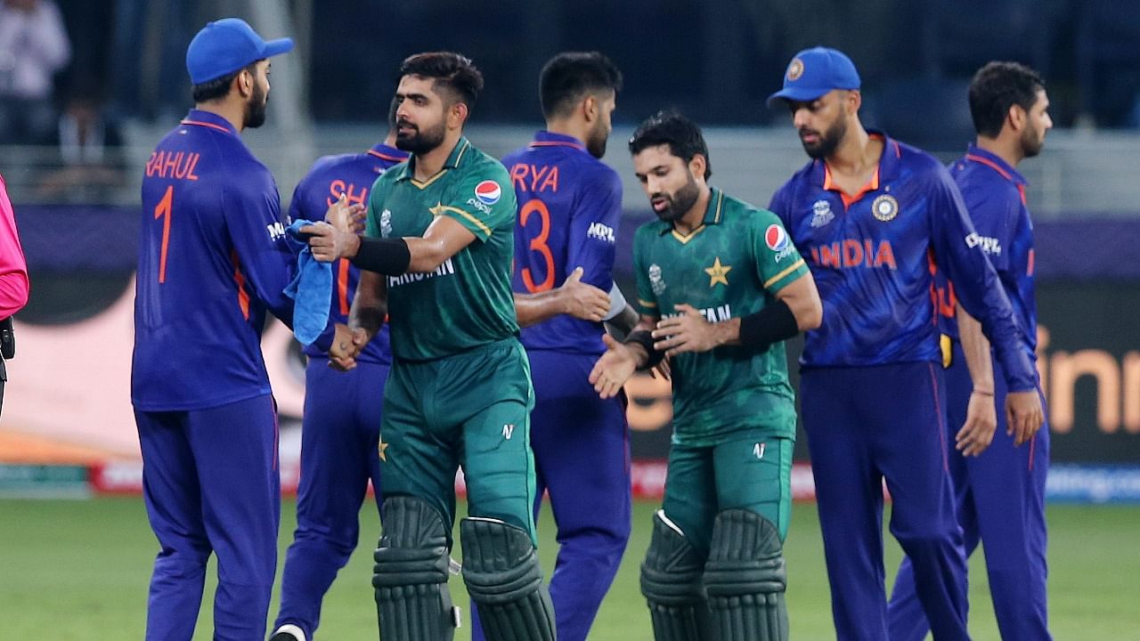 Pakistan's Mohammad Rizwan and Babar Azam shake hands with India players after winning the match by 10 wickets. Credit: Reuters Photo