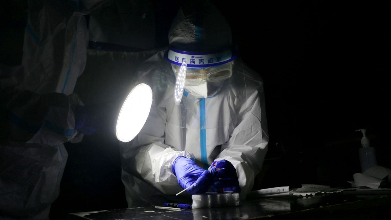 This photo taken on October 20, 2021 shows a medical worker collecting a sample to be tested for the Covid-19 coronavirus in Zhangye in China's northwestern Gansu province. Credit: AFP Photo