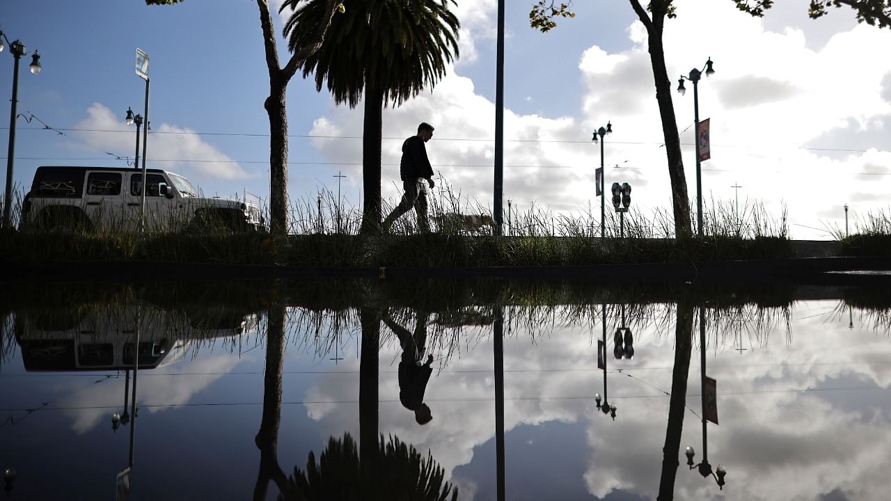Local resident walks a dog along flooded parking lot after a powerful storm drenched northern California. Credit: Reuters Photo