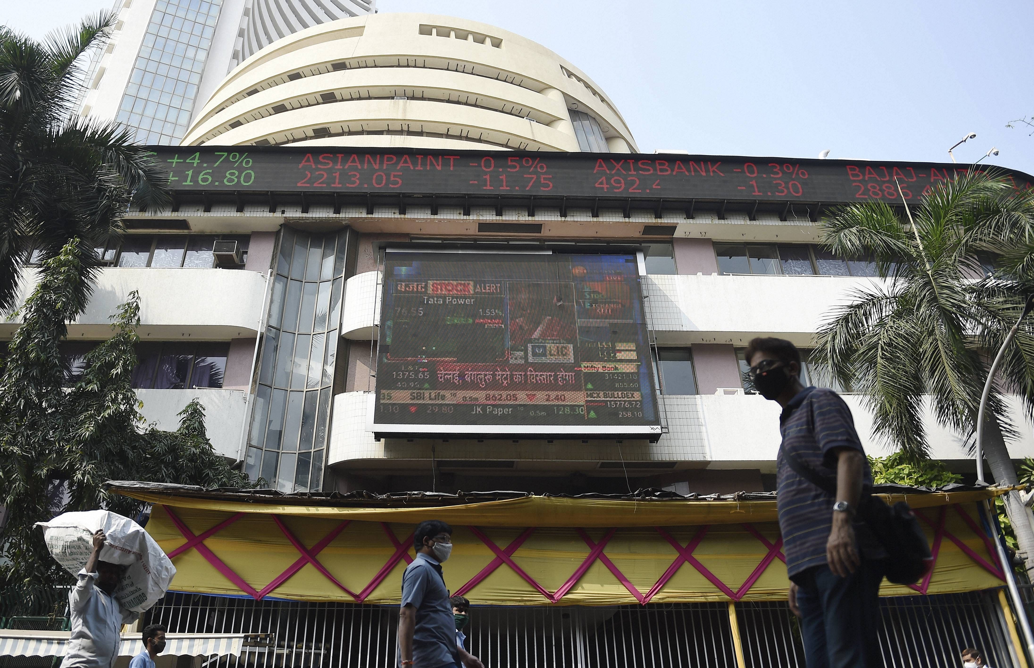 People walk past a digital screen, displaying stock prices, on the facade of Bombay Stock Exchange (BSE). Credit: PTI Photo