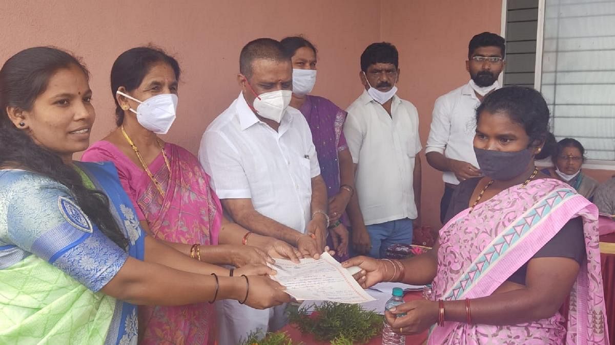 MLA M P Appachu Ranjan hands over a title deed to a beneficiary in Byadagotta.