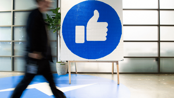 Facebook employee walks by a sign displaying the 'like' sign at Facebook's corporate headquarters. Credit: AFP Photo