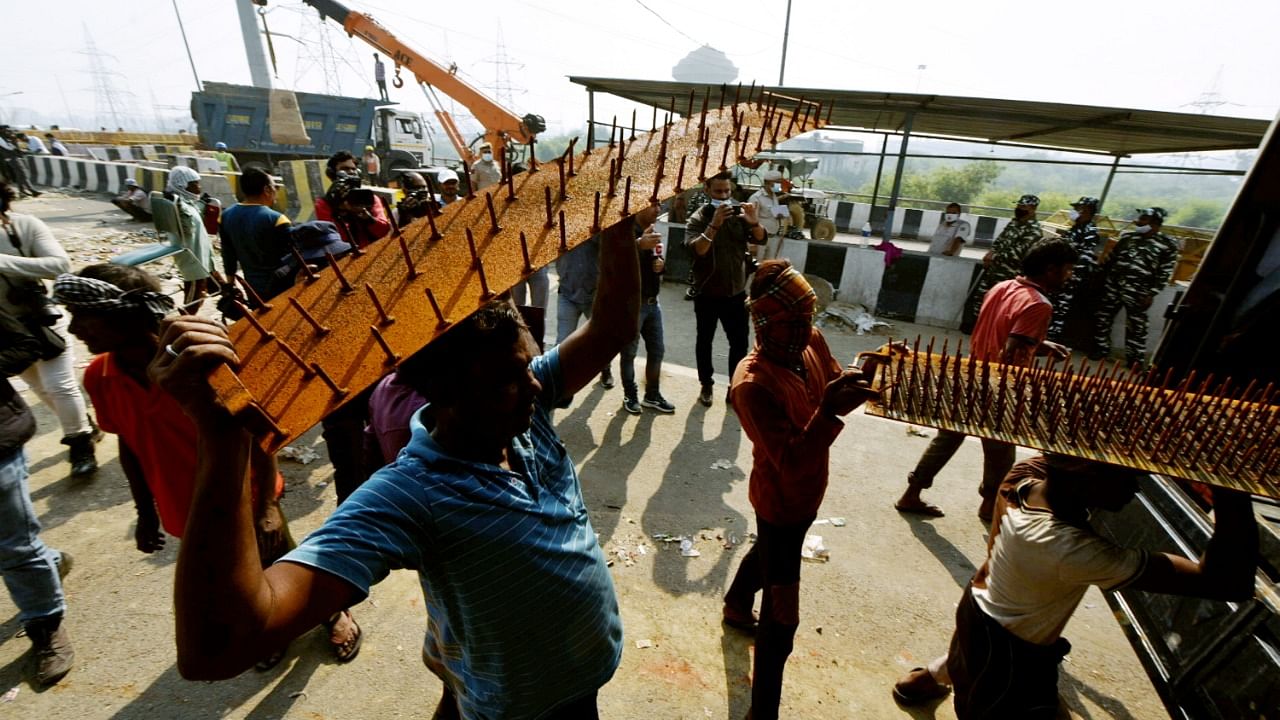 Police barricades being removed from the farmers' protest site at Ghazipur border, in Ghaziabad. Credit: PTI Photo
