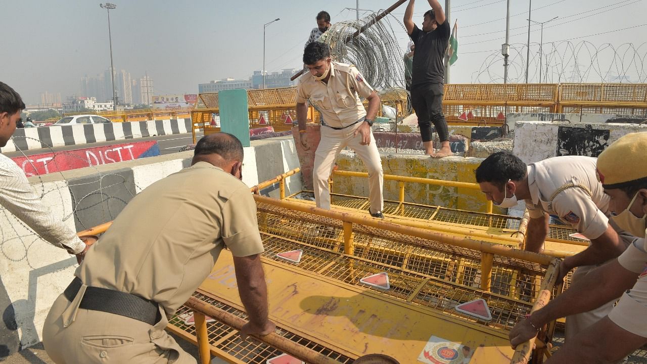 Delhi Police personnel remove barricades from the farmers' protest site at Ghazipur border in New Delhi. Credit: PTI Photo